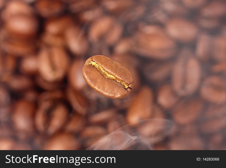 Coffee bean in smoke on the background of coffee beans (selective focus)