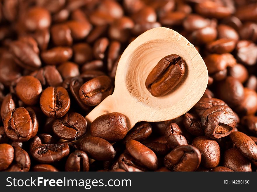 Coffee beans in a spoon, on the background of coffee (selective focus)