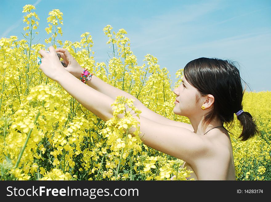 A beautiful girl taking photos of oilseed flowers. A beautiful girl taking photos of oilseed flowers