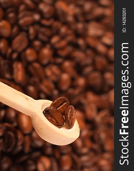 Coffee beans in a spoon, on the background of coffee (selective focus)