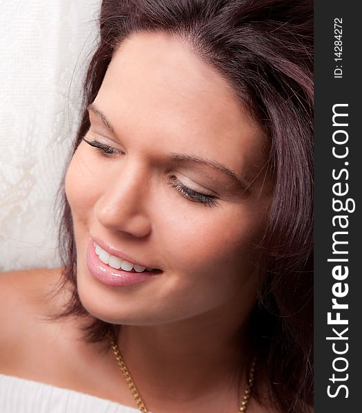 A soft, close-up portrait of a smiling woman set against a lacy white backdrop. A soft, close-up portrait of a smiling woman set against a lacy white backdrop