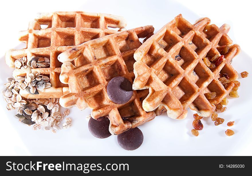 Waffles from integral wholegrain with chocolate, grain and dried grapes on plate. Waffles from integral wholegrain with chocolate, grain and dried grapes on plate
