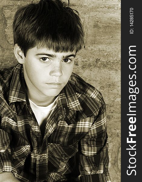 Serious teenager sitting alone against a brick wall