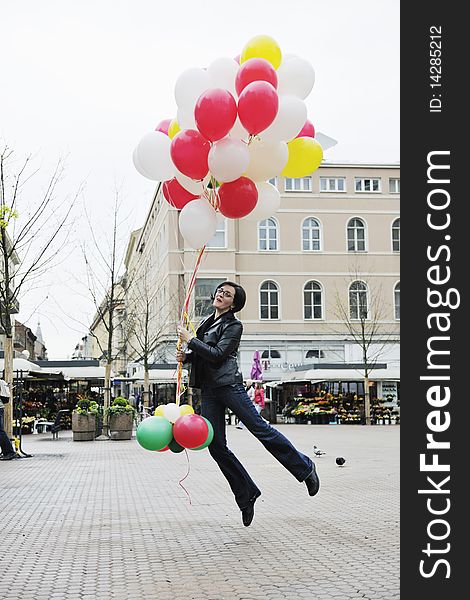 Happy young woman holding lots of ballons and try to fly. Happy young woman holding lots of ballons and try to fly