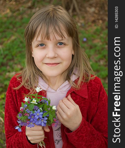 Portrait of a beautiful smiling girl of school age with a bouqete of snowdrops. Portrait of a beautiful smiling girl of school age with a bouqete of snowdrops