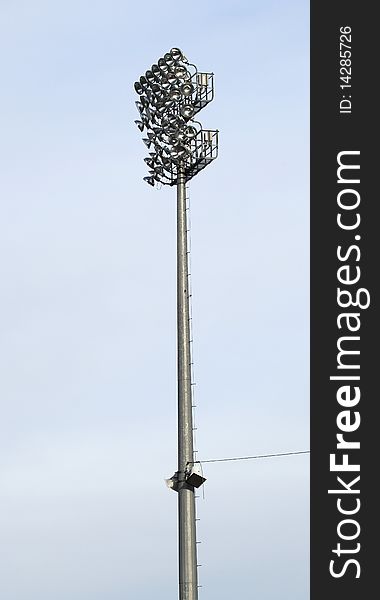 A stadium light against a blue sky at a baseball outdoor stadium ballpark. A stadium light against a blue sky at a baseball outdoor stadium ballpark.