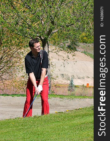 Young male golfer preparing to play a shot from the bunker. Young male golfer preparing to play a shot from the bunker