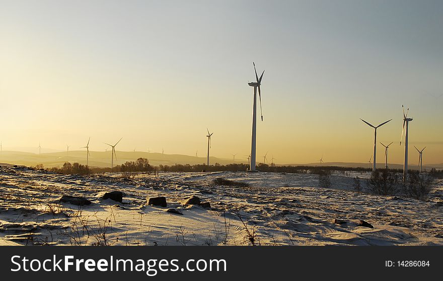 Wind power generator against dramatic sunrise or sunset in snow field. Wind power generator against dramatic sunrise or sunset in snow field