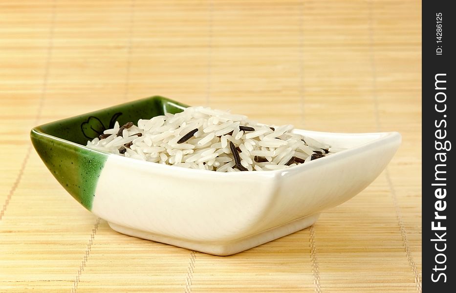 A bowl of mixed rice on a bamboo mat. A bowl of mixed rice on a bamboo mat