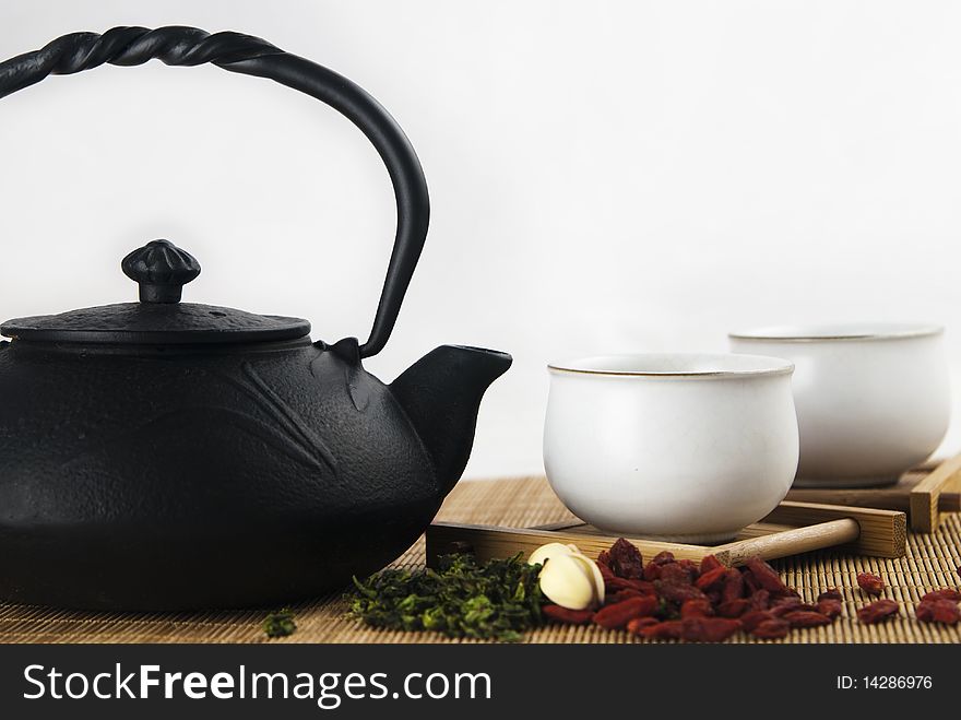 A iron teapot and two cups filled with green tea