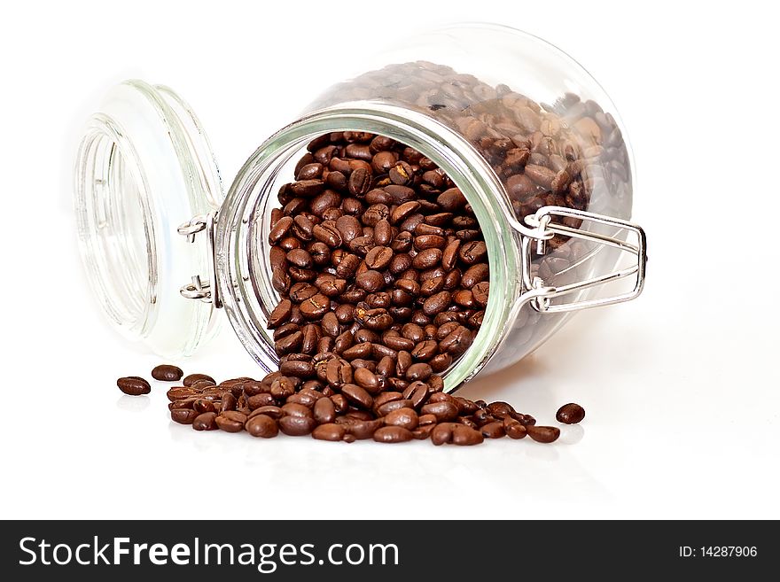 Coffee beans spilling out of a cristal jar on a white background