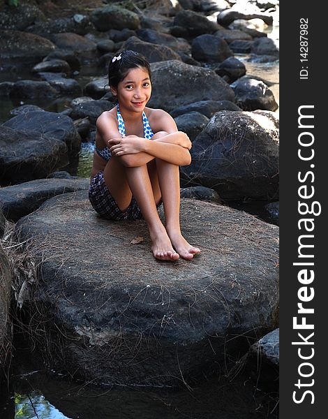 Young asian lady sitting in a rock by the river. Young asian lady sitting in a rock by the river