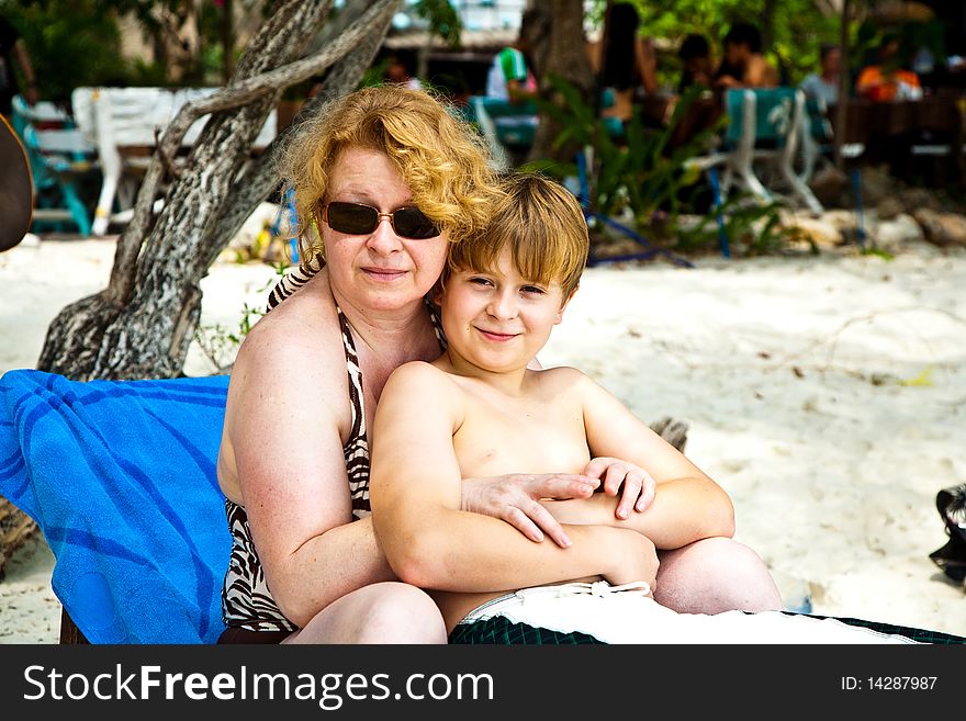 Mother is spooning with her happy smiling son at the beautiful beach