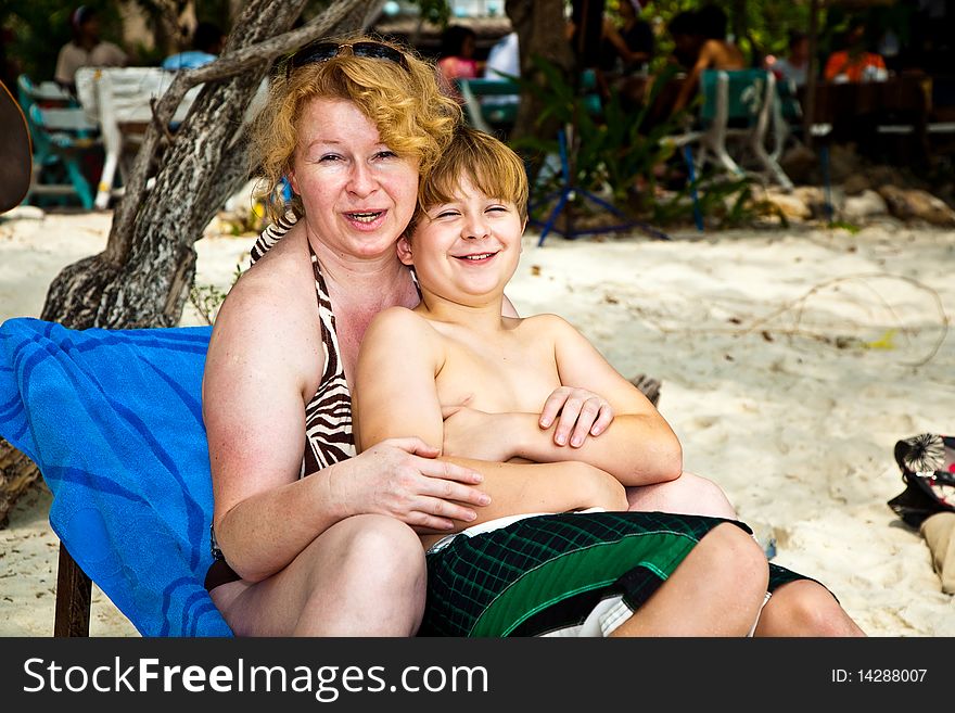 Mother is spooning with her happy smiling son at the beautiful beach