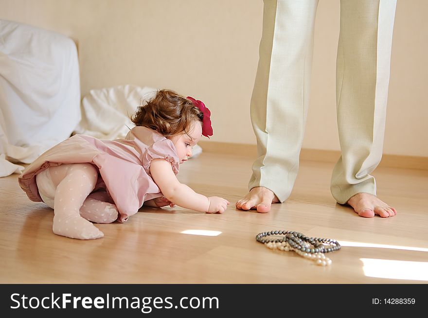 Cute baby girl lies on a floor and plays with feet of the daddy. Cute baby girl lies on a floor and plays with feet of the daddy