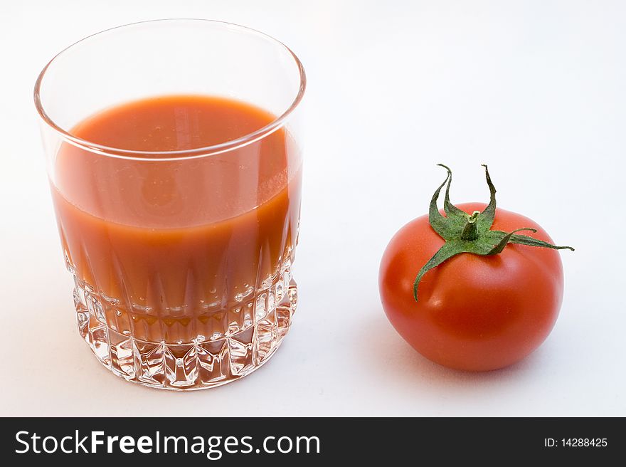 Tomato juice  and tomato at white plate close-up on a white background. Tomato juice  and tomato at white plate close-up on a white background