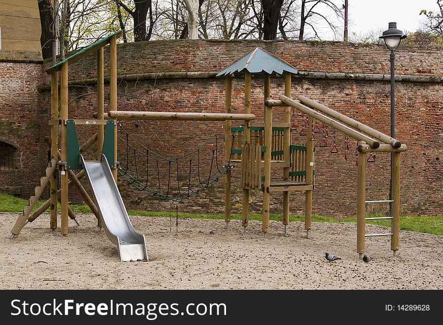 Wooden playground park with slide by old town walls