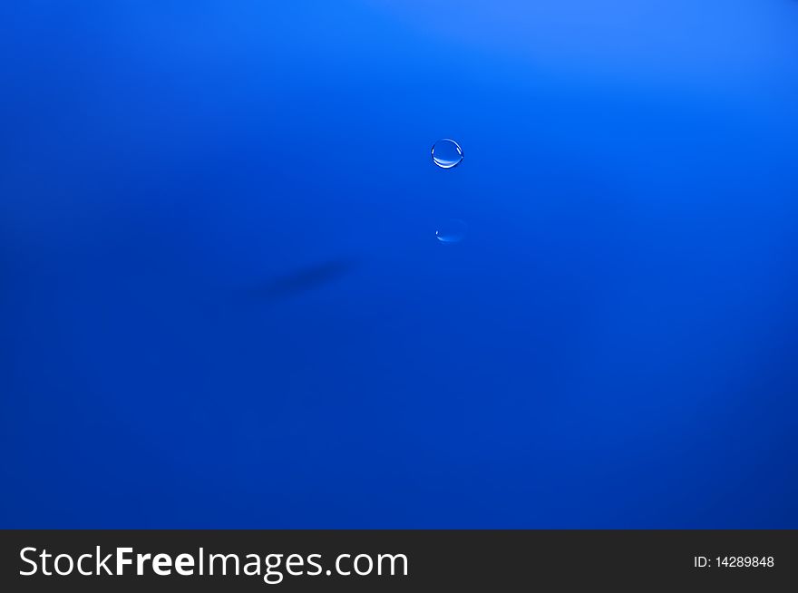 Blue waterdrop near water surface