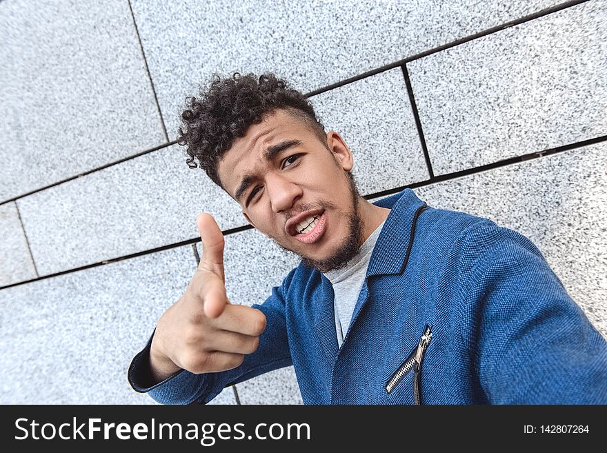 Freestyle. Mulatto guy standing isolated on wall taking selfie pointing at camera cool close-up