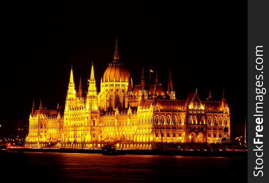 The Hungarian Parliament in Neo Gothic style from across the Danube in panoramic night view with tour boat under black sky. Famous, popular Budapest landmark and tourist attraction. Budapest nightscape. Tourism and travel concept. The Hungarian Parliament in Neo Gothic style from across the Danube in panoramic night view with tour boat under black sky. Famous, popular Budapest landmark and tourist attraction. Budapest nightscape. Tourism and travel concept.