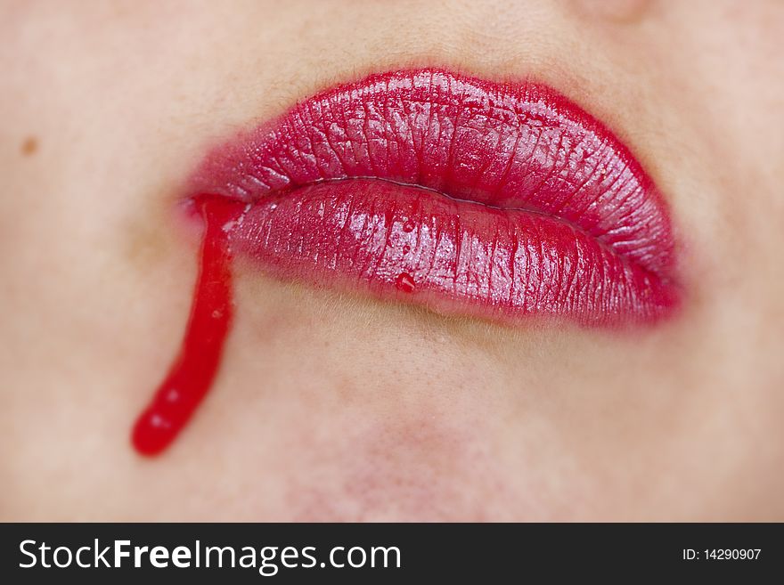 Close up view of some strawberry syrup on red lips. Close up view of some strawberry syrup on red lips.