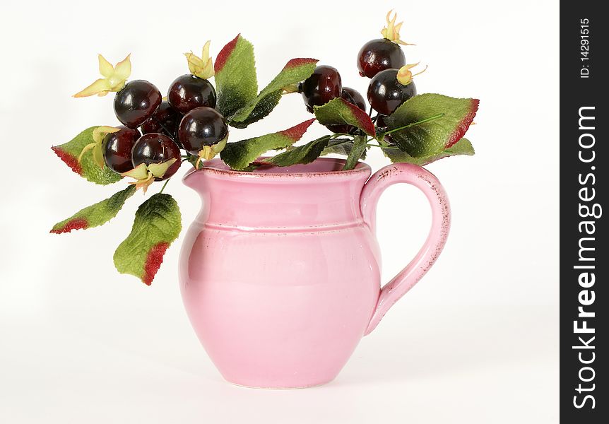 Pink ceramic jar with a sprig of souvenir berries, isolated