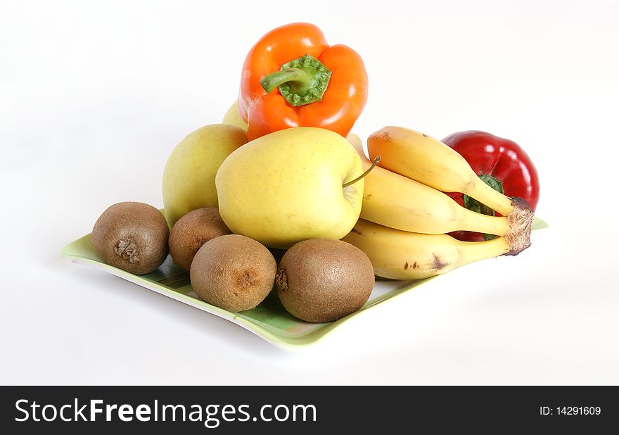 Still life with fruits and vegetables on a saucer on a white background