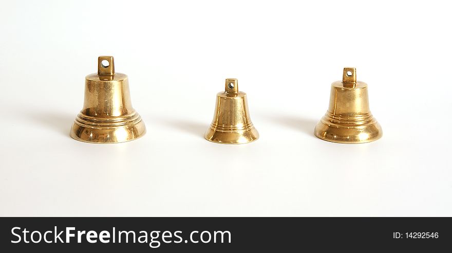 Small brass bells on a white background with shadows