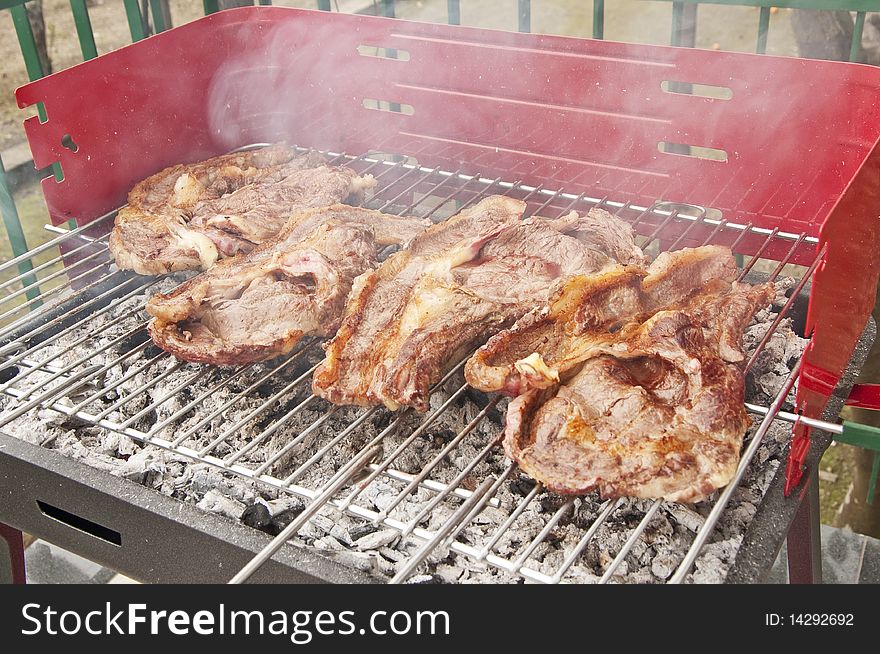 Some slices of beef on the grill with smoke. Some slices of beef on the grill with smoke