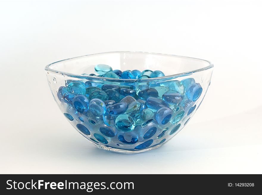 Brilliant blue stones from a glass in transparent glass, isolated on white