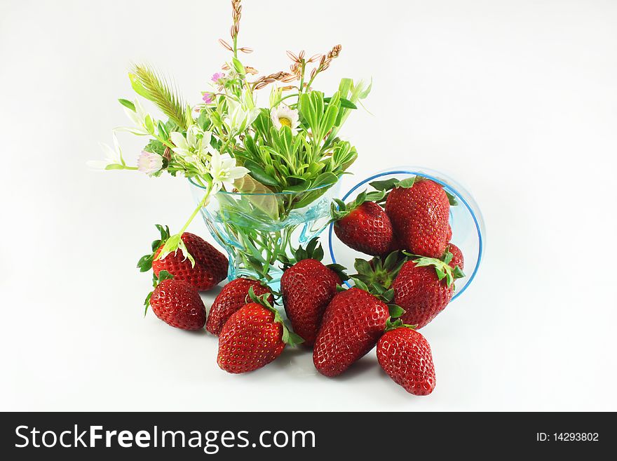 Strawberries and wild flowers in a glass vase