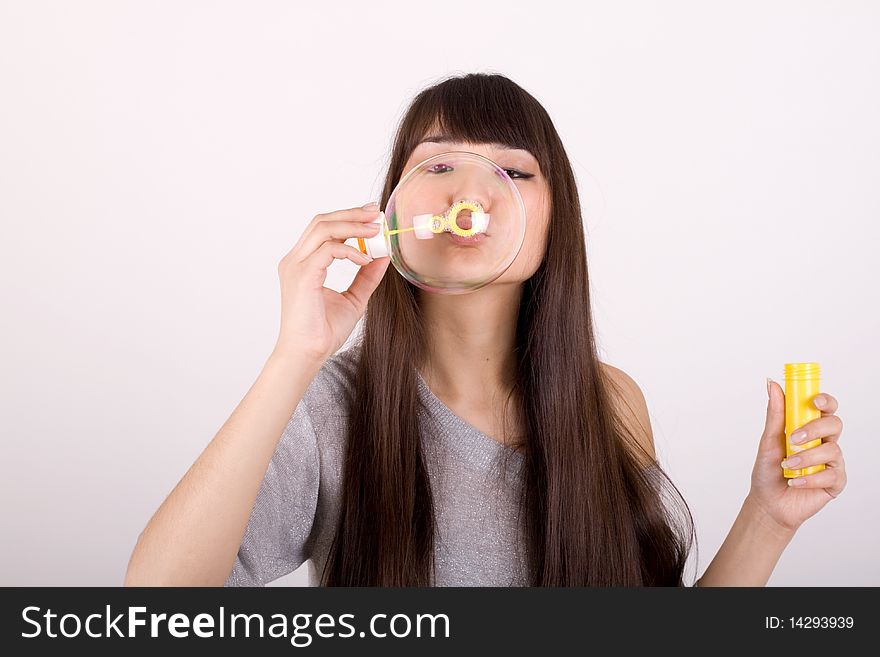 Girl blowing soap bubbles in studio