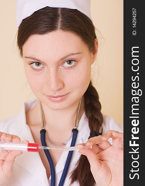 Portrait of young nurse or doctor with medical hat, syringe and stethoscope, studio background. Portrait of young nurse or doctor with medical hat, syringe and stethoscope, studio background.