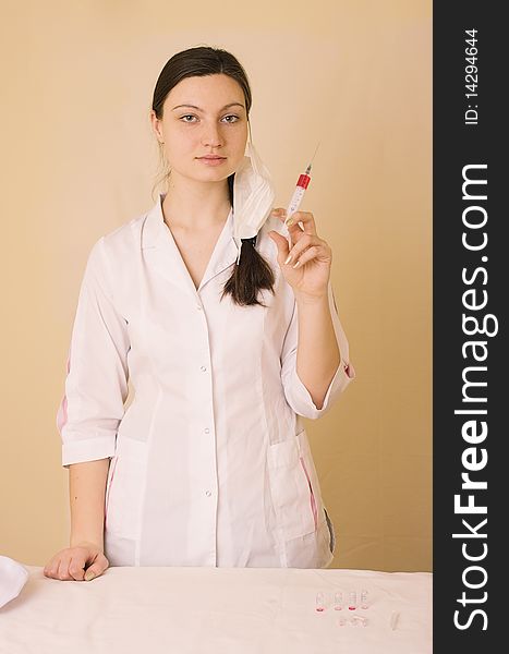 Portrait of young nurse or doctor with surgical face mask and syringe, studio background. Portrait of young nurse or doctor with surgical face mask and syringe, studio background.