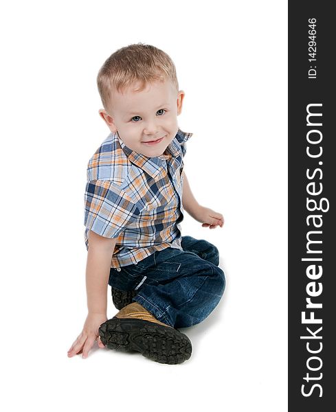 Smiling little boy sit on a floor, isolated on white