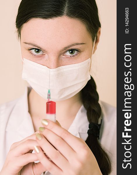 Portrait of young nurse or doctor with surgical face mask and syringe, studio background. Portrait of young nurse or doctor with surgical face mask and syringe, studio background.