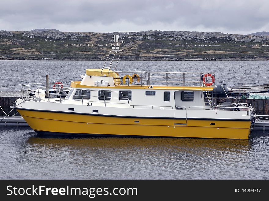 Big, yellow boat in port tied on dock