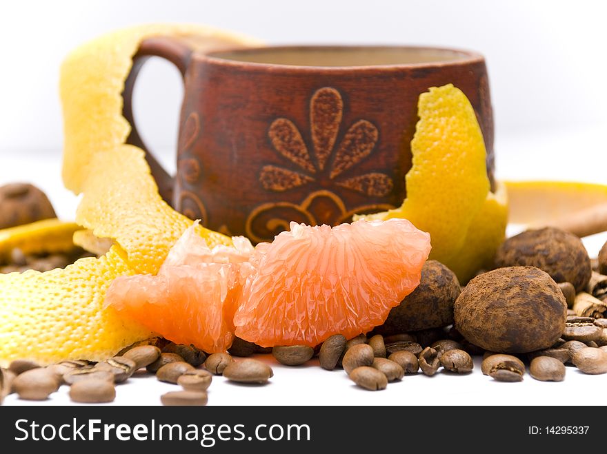 Juicy slice of ripe grapefruit on the background of a coffee cup, grapefruit peel, coffee beans and chocolate truffles. Juicy slice of ripe grapefruit on the background of a coffee cup, grapefruit peel, coffee beans and chocolate truffles