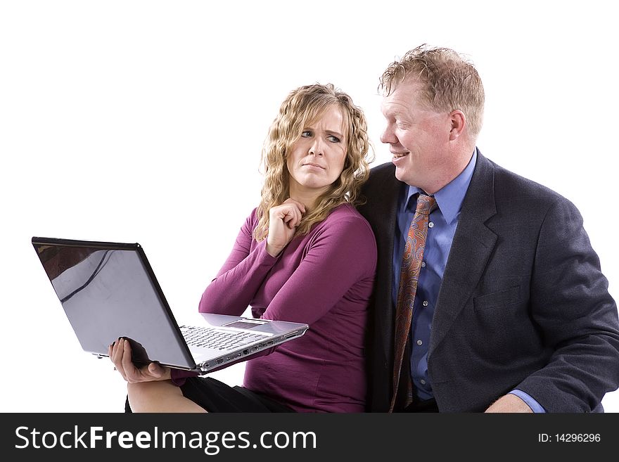 A business woman and man working together on a laptop he is happy about something and she is showing her frustration. A business woman and man working together on a laptop he is happy about something and she is showing her frustration.