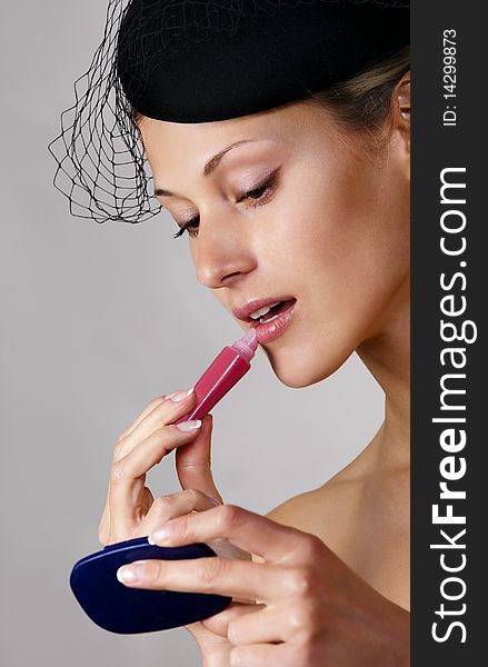 Caucasian retro-styled model applying cosmetics on her face. Caucasian retro-styled model applying cosmetics on her face