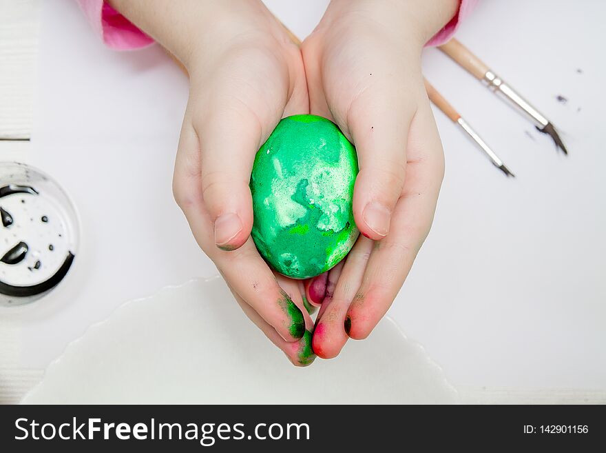 A Flat Lay With Kid`s Hands Painting Easter Eggs On White Wooden Table