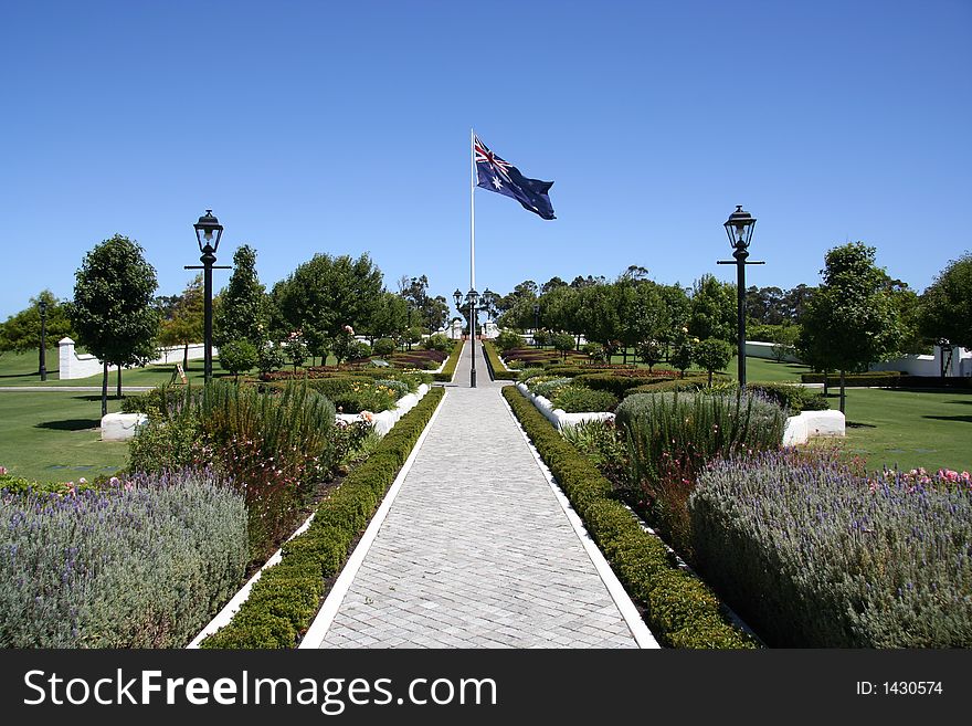 A cottage garden path leads to a big Australian flag blowing in the wind. A cottage garden path leads to a big Australian flag blowing in the wind