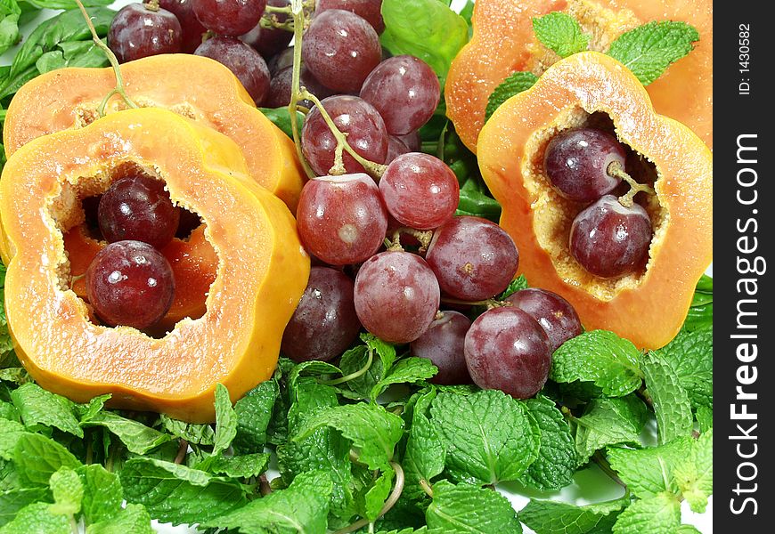 Papaya sliced whit red grapes on mint leaves