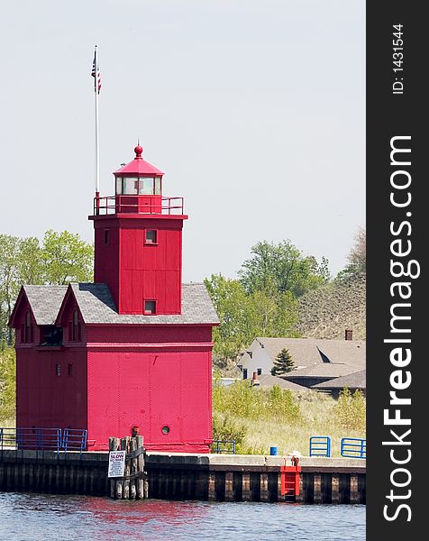 An old red lighthouse at the end of a pier on a lake shore