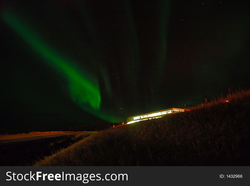 Northern lights over a lit up building. Northern lights over a lit up building.