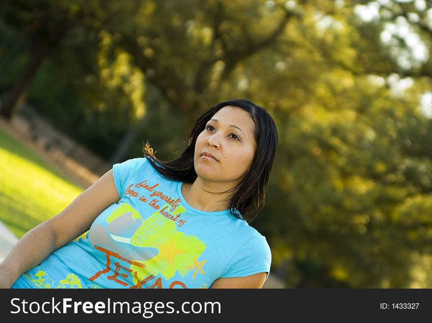 Half body of a girl sitting with green tree park background. Half body of a girl sitting with green tree park background