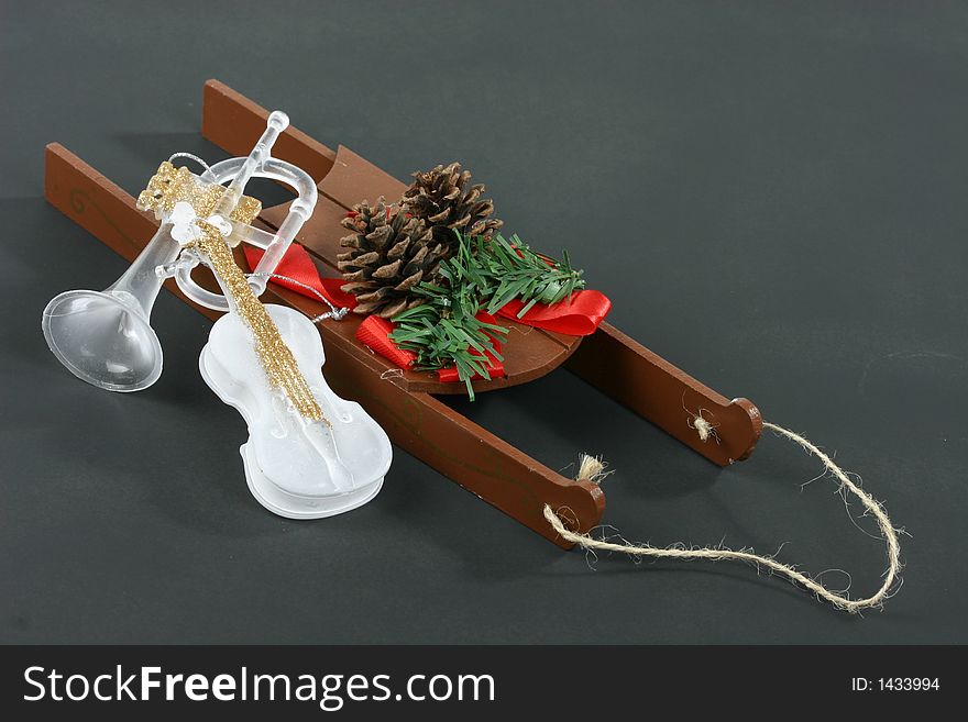 Christmas sleigh with pine cones, red ribbon, greenery, and musical instruments. Christmas sleigh with pine cones, red ribbon, greenery, and musical instruments