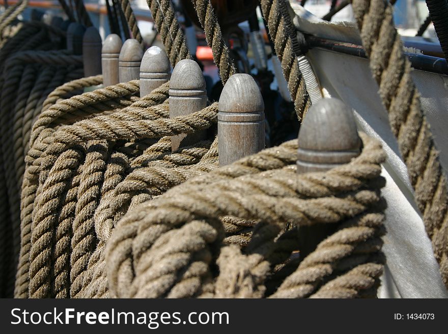 Row of ropes tied around wooden cleats (focus on the middle) photographen on a tall ship