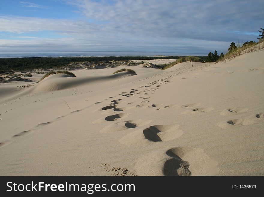 Footprints in sand dune under cloudy sky. Footprints in sand dune under cloudy sky