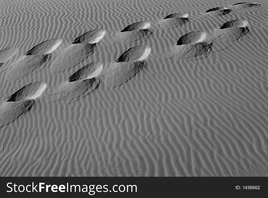 Black and white image of footsteps in the sand dunes